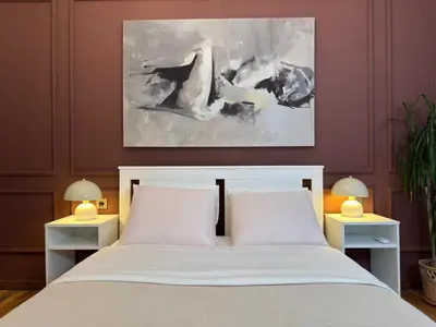 a bedroom with a white bed with two white tables at Historic High-Ceiling 2-Flat Combo - Taksim in Istanbul