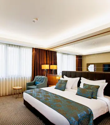 a hotel room with a large bed and a chair at Anemon Bursa Gönlüferah Termal&Spa Otel in Bursa