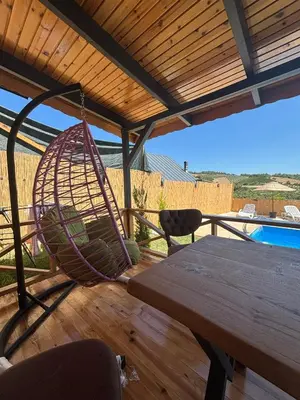 a hammock on a patio with a table and a pool at Uysal Dağevleri in Bilecik