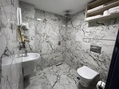 a marble bathroom with a sink and a toilet at Hotel Prima in Istanbul