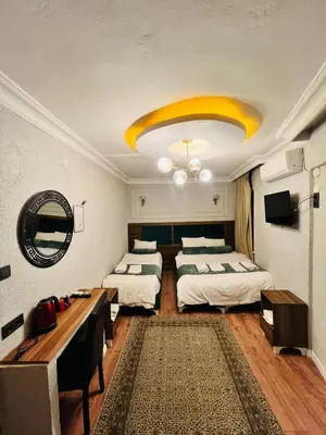 a room with two beds and a table and a mirror at Pembe Köşk Old City Center in Istanbul