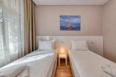 two beds in a small room with a lamp at Port Apart Hotel in Istanbul