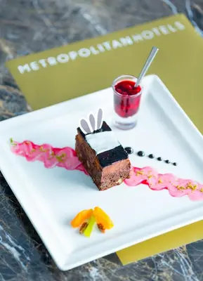 a piece of cake on a plate with a drink at Metropolitan Hotels Taksim in Istanbul