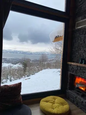 a room with a large window with a fireplace and snow at papatya in Sapanca