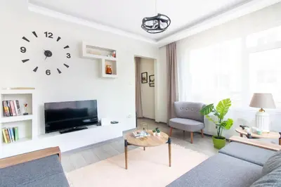 a living room with a couch and a clock on the wall at Pretty Corner Flat with Abundant Light in Kadikoy in Istanbul