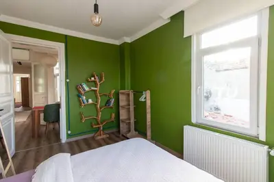 a green room with a bed and a window at Soft and Historic 3BR Home w Iconic Haydarpasa View in Istanbul