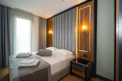 a bedroom with a bed with white sheets and a mirror at Rusel Park Residence in Bahcesehir