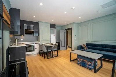 a kitchen and a living room with a couch and a table at Rusel Park Residence in Bahcesehir