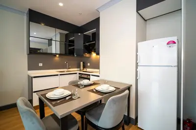 a kitchen with a table and chairs and a refrigerator at Rusel Park Residence in Bahcesehir