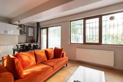 a living room with an orange couch and a kitchen at Cozy Modern 1BR w Patio New Building in Maltepe in Istanbul