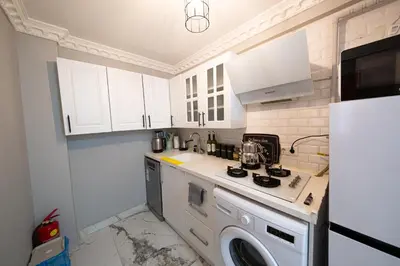 a kitchen with white cabinets and a washing machine at Taksim İstiklalin Kalbinde Konforlu Daire Netflix Wifi in Istanbul