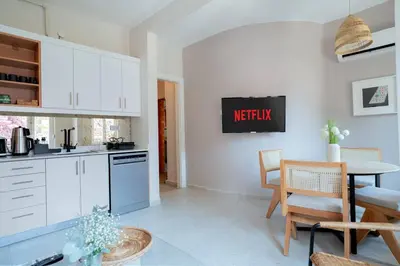 a kitchen with white cabinets and a table and a dining room at Bright and Cozy 2BR Apt In The Center Of Buyukada in Adalar