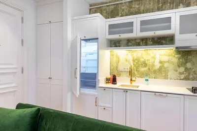 a kitchen with white cabinets and a green couch at Liberty Residence in Istanbul