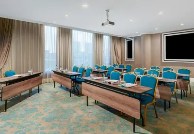 a conference room with tables and chairs and a screen at Kaya İstanbul Fair & Convention in Istanbul
