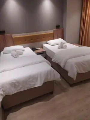two beds with white sheets in a room at Enjoy Suit in Tuzla