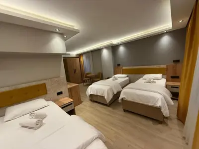 a room with four beds with white sheets at Enjoy Suit in Tuzla