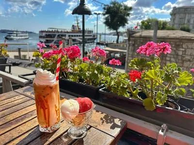 a drink on a wooden table with flowers on a balcony at Levant Pension de Luxe in Istanbul