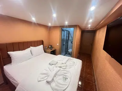 a bedroom with a bed with white sheets and a television at Cemre Homes in Istanbul