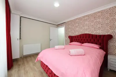 a bedroom with a pink bed with pink pillows on it at Uzay Apartments in Istanbul