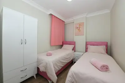 two beds in a small bedroom with pink accents at Uzay Apartments in Istanbul