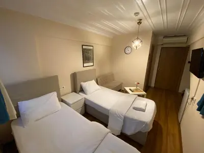 a hotel room with two beds and a clock on the wall at Konak Akaretler Suit in Istanbul