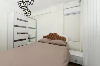 a white bedroom with a bed and a mirror at Kardes Apartment in Istanbul