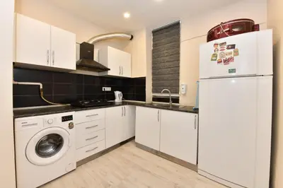 a kitchen with white cabinets and a washer and dryer at Sevim Apartment in Istanbul
