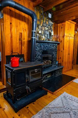 a black stove in a room with a fireplace at Uludag Tatil Evleri & Villa Dogus Uludağ in Bursa