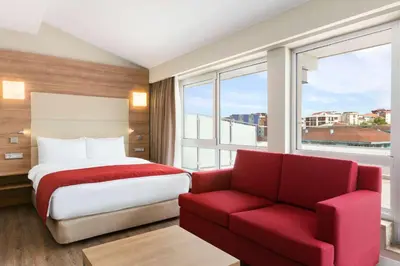 a hotel room with a bed and a red chair at Ramada Encore Istanbul Kartal in Istanbul