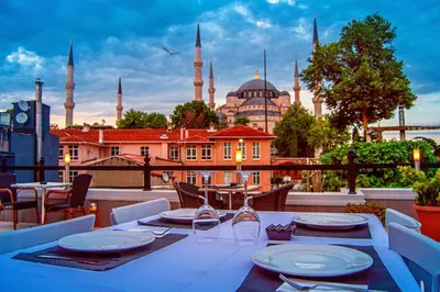 a table on a balcony with a view of a mosque at Sarnic Hotel & Sarnic Premier Hotel(Ottoman Mansion) in Istanbul