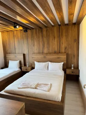 two beds in a room with wooden walls at Lina Apart in Arnavutköy