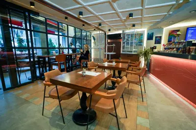a restaurant with tables and chairs and a woman sitting at a counter at Vital Hotel Suites in Istanbul