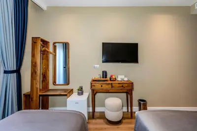 a bedroom with a desk and a tv on the wall at Nenessa Airport Hotel in Arnavutköy