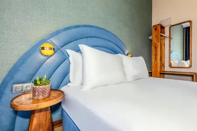 a bedroom with a bed with a blue headboard at Nenessa Airport Hotel in Arnavutköy
