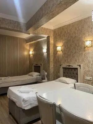 a room with two beds and a table and chairs at Nuray Hotel in Istanbul