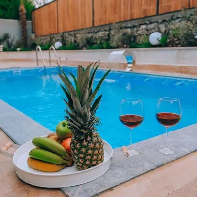 a plate of fruit and wine glasses next to a pool at Çınar home in Sapanca
