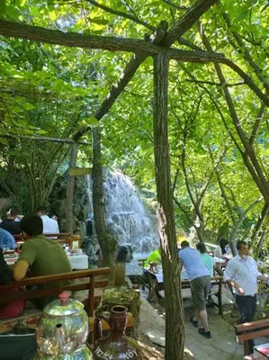 a group of people sitting at tables in front of a waterfall at Köyevi Teras Bungolov in Kartepe