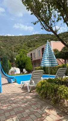 two chairs and an umbrella next to a pool at Ali Baba Butik Otel in Gündoğdu