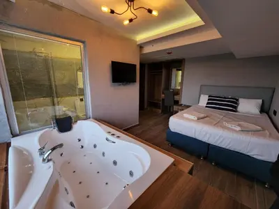 a bathroom with a tub and a bed and a bed and a sink at Martin City Hotel in Bursa
