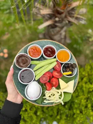a person holding a plate of food with vegetables and sauces at Bohem Hotel in Beykoz