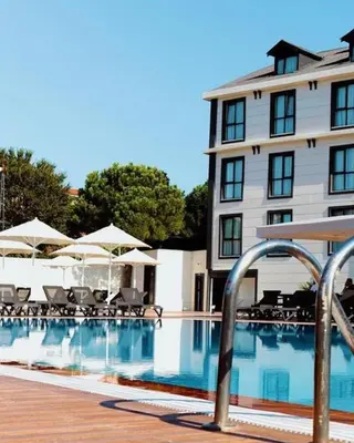 a swimming pool with chairs and umbrellas next to a building at Bohem Hotel in Beykoz