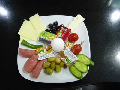 a plate of cheese and vegetables on a table at AG Hotel & Residence Şişli in Istanbul