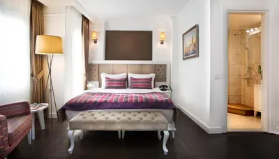 a bedroom with a bed with a bench and a television at Astan Hotel Taksim in Istanbul