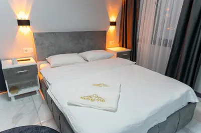 a hotel room with a bed with a white blanket at Merkez Otel in Cerkezkoy
