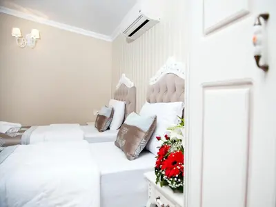 a white bedroom with two beds with flowers on a table at Kadi Konagi Thermal Hotel in Bursa