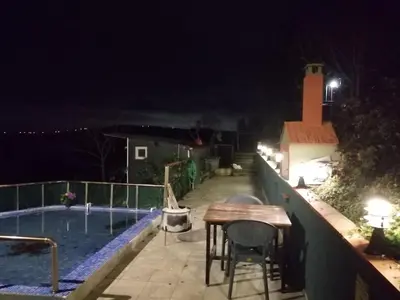 a table and chairs next to a swimming pool at night at Nerry's Garden Izmit - Rose in Yukarı Mecidiye