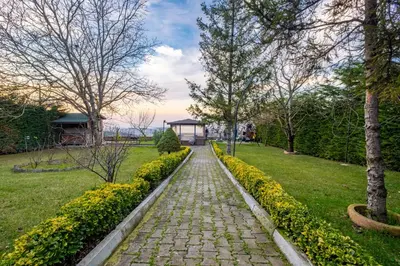 a stone path in a park with trees and flowers at Uludağ Tatil Evleri & Villa Seyir in Yigitali