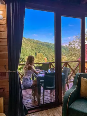 a woman sitting at a table with a laptop on a balcony at Şifaköy Bungalov in Sapanca