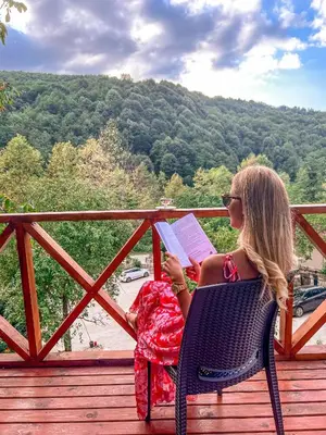 a woman sitting in a chair reading a book at Şifaköy Bungalov in Sapanca