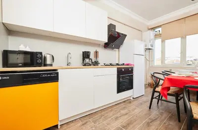 a kitchen with white cabinets and a table with chairs at Stunning 3BR 3Bathroom 3AC near Metro D5 in Istanbul